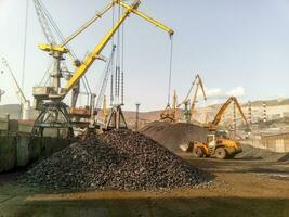 Cargo industrial port, port cranes. Loading of anthracite. Transportation of coal. Heap of coal photo