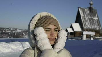 a cute girl stands in the cold against the church. A girl warms face in the cold video
