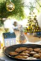 Festive Christmas decor in table, homemade cakes for breakfast, bakery cookies. Cozy home, christmas tree with fairy lights garlands. New Year, christmas mood photo