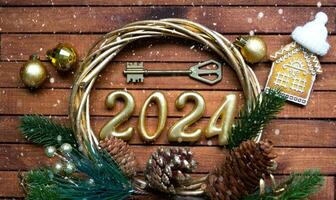 House key with keychain cottage on festive brown wooden background with stars, lights of garlands. New Year 2024 wooden letters, greeting card. Purchase, construction, relocation, mortgage, insurance photo