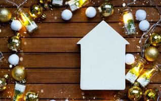 Tiny white house mock up on wooden background with Christmas decor layout and copy space. Gift for New Year, Christmas. Building, project, moving to new house, mortgage, rent and purchase real estate photo