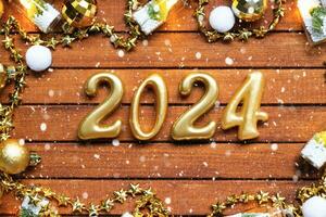 Happy New Year wooden numbers 2024 on cozy festive brown wooden background with sequins, snow, lights of garlands. Greetings, postcard. Calendar, cover photo