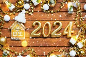 House key with keychain cottage on festive brown wooden background with stars, lights of garlands. New Year 2024 wooden letters, greeting card. Purchase, construction, relocation, mortgage, insurance photo