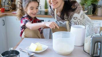 Mom and daughter in the white kitchen are preparing cookies, add ingredients. Family day, preparation for the holiday Christmas, learn to cook delicious pastries, cut shapes out of dough with molds photo