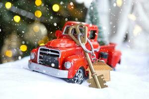 Red retro car with a Christmas tree decorates with the house key in the pickup truck for Christmas. Buying a home, moving, mortgage, loan, real estate, festive mood, New Year photo