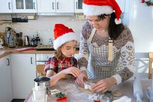 Mom and daughter in the white kitchen are preparing cookies for Christmas and new year. Family day, preparation for the holiday, learn to cook delicious pastries, cut shapes out of dough with molds photo