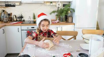 Daughter learning to cook helps in the white kitchen knead the dough in the bowl for gingerbread and cookies for Christmas and new year. Put the ingredients photo