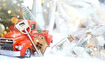 Red retro car with a Christmas tree decorates with the house key in the pickup truck for Christmas. Buying a home, moving, mortgage, loan, real estate, festive mood, New Year photo