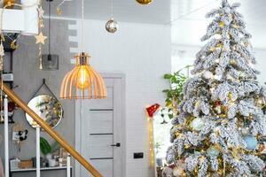 Festive Christmas decor in the hallway in the loft style with a retro wooden lampshade with a snowy Christmas tree and fairy lights. New Year, Christmas mood, cozy home. photo