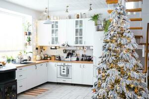 Festive Christmas decor in white kitchen, modern rustic interior with a snowy Christmas tree and fairy lights. New Year, Christmas mood, cozy home. The general plan photo