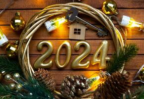 House key with keychain cottage on festive brown wooden background with stars, lights of garlands. New Year 2024 wooden letters, greeting card. Purchase, construction, relocation, mortgage, insurance photo