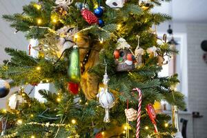 el gato gracioso está sentado en el árbol de navidad. vandalismo de una mascota, sabotaje, daño a la decoración. navidad, año nuevo. foto