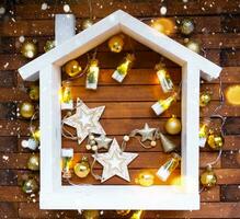 Tiny frame house on wooden background with Christmas decor layout and copy space. Gift for New Year, Christmas. Building, project, moving to new house, mortgage, rent and purchase real estate photo