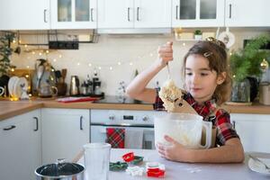 Daughter learning to cook helps in the white kitchen knead the dough in the bowl for gingerbread and cookies for Christmas and new year. Put the ingredients photo