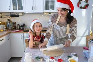 Mom and daughter in the white kitchen are preparing cookies for Christmas and new year. Family day, preparation for the holiday, learn to cook delicious pastries, cut shapes out of dough with molds photo