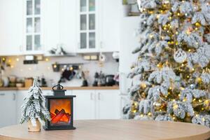 Festive Christmas decor on a round empty table with space for text in white kitchen, modern interior with a Christmas tree and fairy lights. New Year, Christmas mood, cozy home. photo