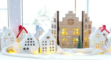 Cozy Christmas decor tiny house of small size on window sill with snow outside the window. Gift for New Year. Insurance, moving to new house, mortgage, rent and purchase real estate photo