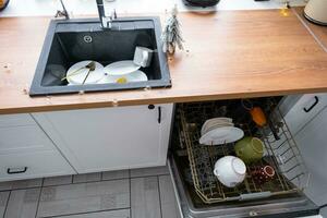 A lot of dirty dishes in the dishwasher in the festive kitchen. Helping the hostess, economy and ecology. Cleaning in the kitchen for the holidays of Christmas and New Year, after the feast and guests photo