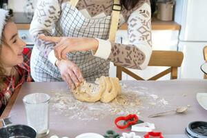 Mom and daughter in the white kitchen are preparing cookies for Christmas and new year. Family day, preparation for the holiday, learn to cook delicious pastries, cut shapes out of dough with molds photo