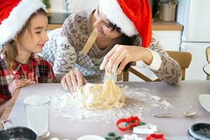 Mom and daughter in the white kitchen are preparing cookies for Christmas and new year. Family day, preparation for the holiday, learn to cook delicious pastries, cut shapes out of dough with molds photo