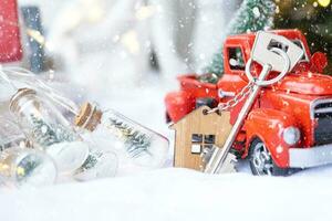 Red retro car with a Christmas tree decorates with the house key in the pickup truck for Christmas. Buying a home, moving, mortgage, loan, real estate, festive mood, New Year photo