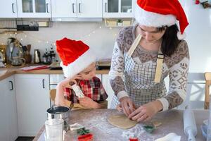 Mom and daughter in the white kitchen are preparing cookies for Christmas and new year. Family day, preparation for the holiday, learn to cook delicious pastries, cut shapes out of dough with molds photo