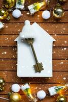 Key to house with a keychain tiny home on wooden background with Christmas decor layout. Gift for New Year, Christmas. Building, project, moving to new house, mortgage, rent and purchase real estate photo