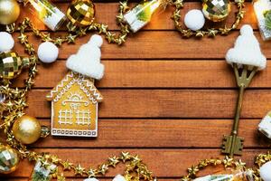 Key to house with a keychain tiny home on wooden background with Christmas decor layout. Gift for New Year, Christmas. Building, project, moving to new house, mortgage, rent and purchase real estate photo