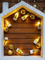 Tiny frame house on wooden background with Christmas decor layout and copy space. Gift for New Year, Christmas. Building, project, moving to new house, mortgage, rent and purchase real estate photo