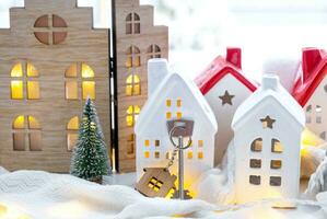 llave y minúsculo casa de un pequeño Talla en acogedor hogar con Navidad decoración en ventana umbral. regalo para nuevo año. seguro, Moviente a nuevo casa, hipoteca, alquilar y compra real inmuebles foto