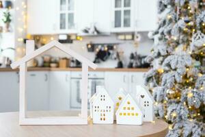 Cozy Christmas decor tiny house of small size on table of festive white modern kitchen. Gift for New Year. Insurance, moving to new house, mortgage, rent and purchase real estate photo