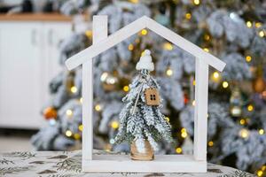 llave en Navidad árbol y minúsculo casa en acogedor hogar con Navidad decoración en mesa de festivo blanco cocina. regalo para nuevo año. seguro, Moviente a nuevo casa, hipoteca, alquilar y real inmuebles foto