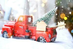 Red retro car with a Christmas tree decorates with the house key in the pickup truck for Christmas. Buying a home, moving, mortgage, loan, real estate, festive mood, New Year photo