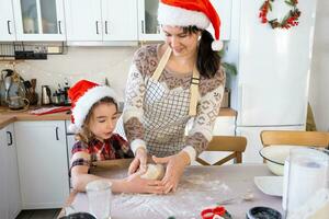 Mom and daughter in the white kitchen are preparing cookies for Christmas and new year. Family day, preparation for the holiday, learn to cook delicious pastries, cut shapes out of dough with molds photo