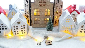 llave y minúsculo casa de un pequeño Talla en acogedor hogar con Navidad decoración en ventana umbral. regalo para nuevo año. seguro, Moviente a nuevo casa, hipoteca, alquilar y compra real inmuebles foto
