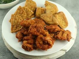 tempe and crispy chicken and tamarind vegetables and spinach, on a wooden table, selective focus photo