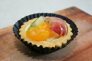 Fruit pie healthy dessert dish with cream cheese filling, garnished with kiwi, grapes, and oranges photo