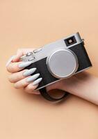 Woman's hand with grey nail polish holding camera photo