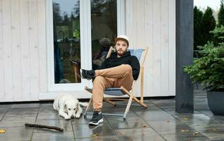 joven hombre sentado con perro en terraza foto
