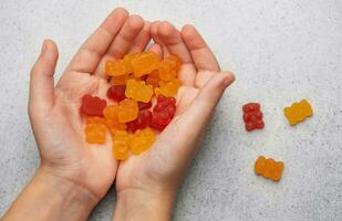 A girl holds a gummy bear vitamines in her hands photo