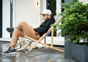 Young man sitting with dog on terrace photo