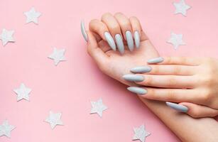 Hands with grey manicure on a pink background photo