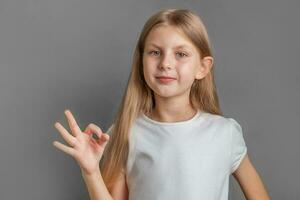 A little blonde  girl shows the ok sign photo