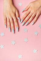 Hands with grey manicure on a pink background photo
