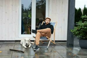 joven hombre sentado con perro en terraza foto