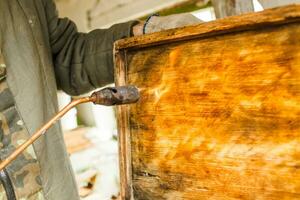 Procesando de abeja marcos y urticaria para el miel cosecha estación. disparo el de madera partes de el colmena con un soplete. apicultura trabajo en el primavera y después invierno. foto