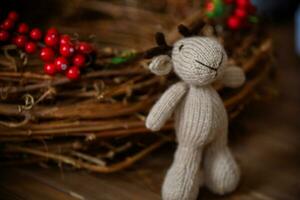 Handmade knitted toy deer on a wooden background. Christmas decoration. photo