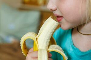 Portrait of a little girl eating a banana. The concept of healthy food. A fresh quick snack photo