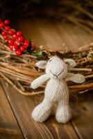 Handmade knitted toy deer in a wicker basket on a wooden background photo