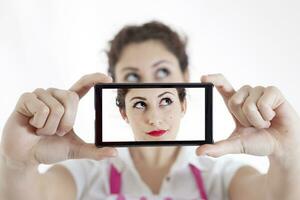 bonito mujer tomando un selfie utilizando su teléfono inteligente foto